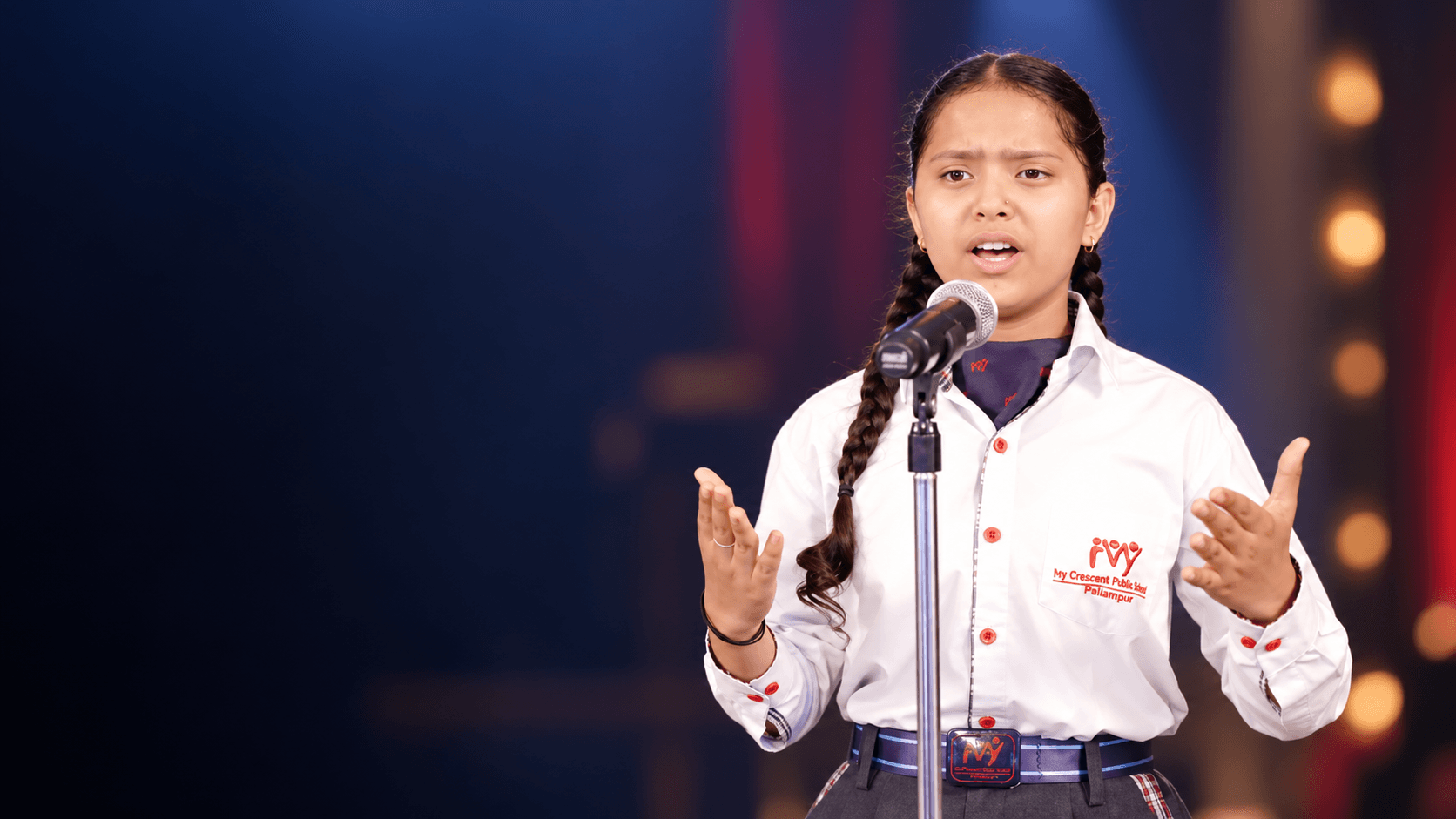 A student speaking confidently at a microphone on stage