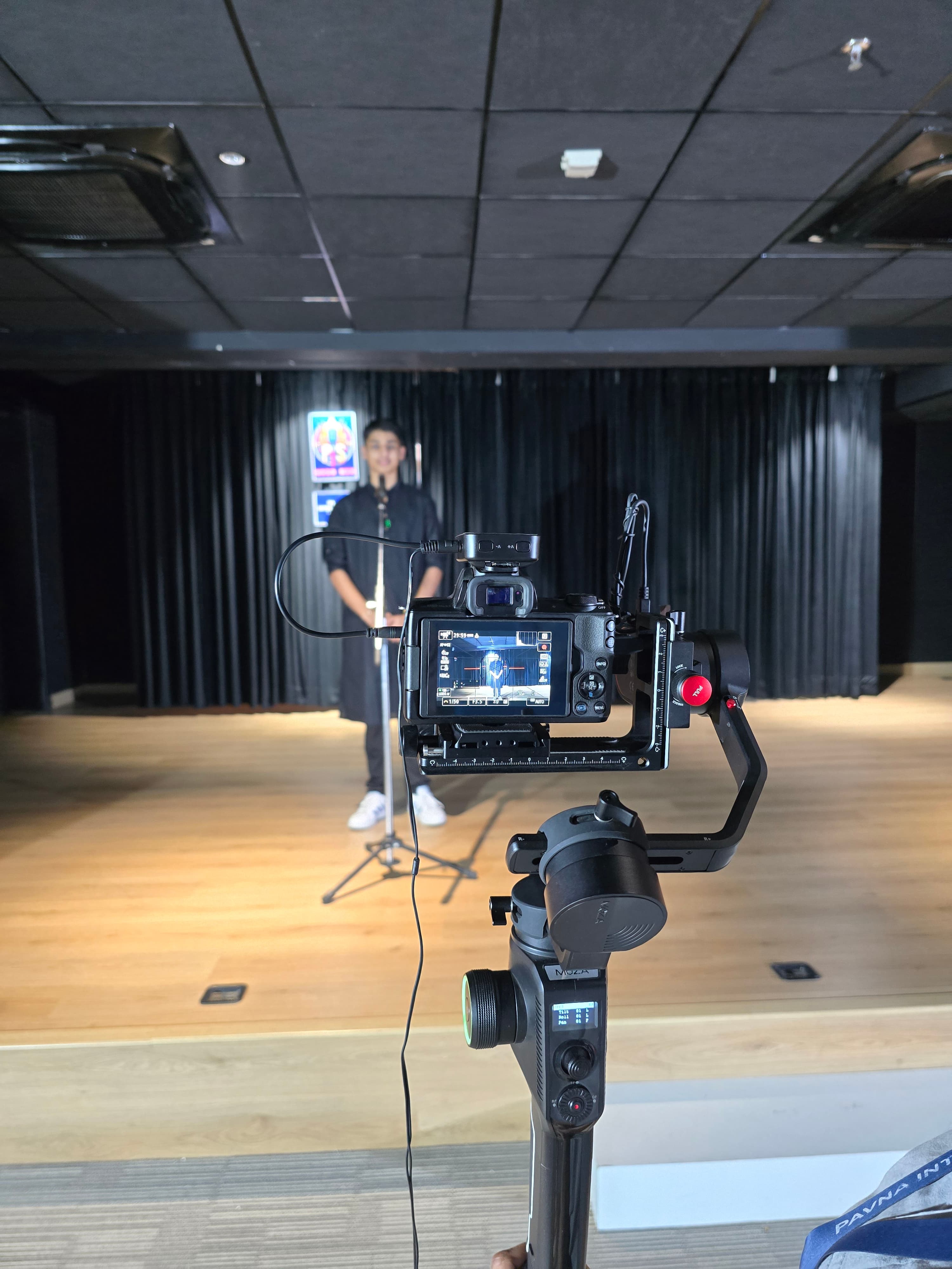 A student preparing to speak while a camera records the stage